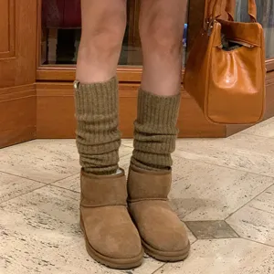 Detailopname van bruine wollen beenwarmers gedragen met stijlvolle laarzen voor de herfstlook.