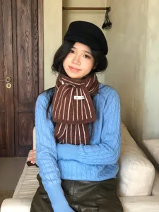 Detailansicht eines kuscheligen braunen Strickschals mit Streifen für Damen im Winter.