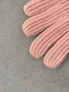 Rosa Strick Winterhandschuhe Detailaufnahme, weiche Rippen Textur warme Fünffinger Handschuhe.