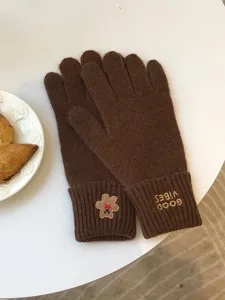 Brown knitted gloves with cute bear embroidery and text detail, soft warm winter accessory.