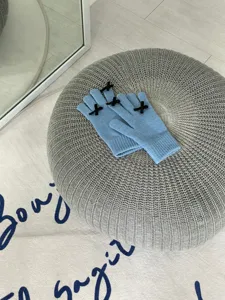 Großaufnahme der hellblauen Strickhandschuhe mit zarten schwarzen Schleifen an den Fingerspitzen.