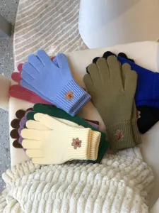 Detailed view of colorful knit touchscreen gloves with cute embroidered bear patches for winter warmth.