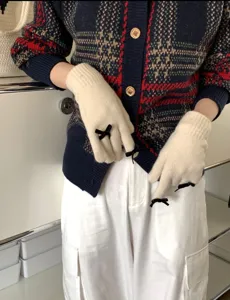 Detailansicht niedlicher Strick-Touchscreen-Handschuhe mit schwarzen Schleifen für den Winter.