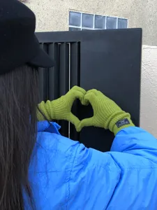 Detailaufnahme grüner Strick-Wollhandschuhe mit Rippbündchen, Herzform präsentierend.