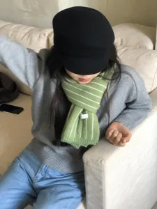 Nahaufnahme eines kuscheligen grünen Strickschals mit Streifenmuster und weicher Textur.