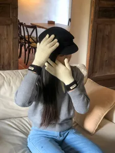 Detailansicht von warmen Strick-Touchscreen-Handschuhen in Creme und Schwarz getragen.