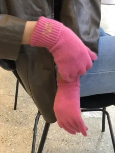Detailed shot of pink winter knit gloves featuring cute embroidery and cozy texture.