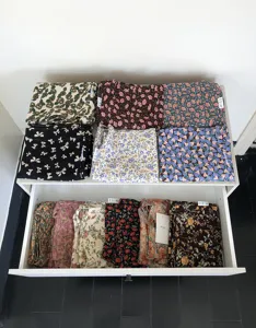 Detaillierte Ansicht verschiedener Canvas-Umhängetaschen mit Blumenmuster ordentlich in Schubladen.