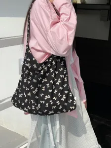 Detail view of the black canvas shoulder bag with white bow print, showing fabric and strap.
