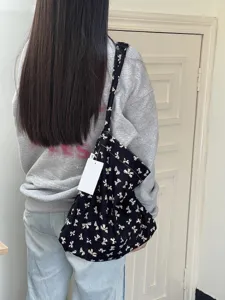 Detail view of the black canvas shoulder bag featuring a cute white bow pattern design.
