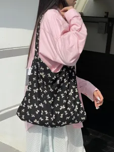 Black canvas shoulder bag featuring allover white bow print, casual style for daily use.