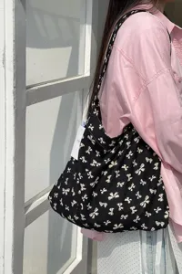 Black canvas shoulder bag with white bow print, casual lazy style tote for students shopping.