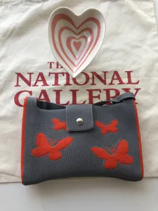 Borsa a tracolla in maglia grigia con motivo a farfalla arancione e dettaglio piattino