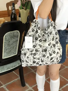 Lässige Blütentasche mit orangefarbenen Griffen, stilvolle Umhängetasche für den Alltag.