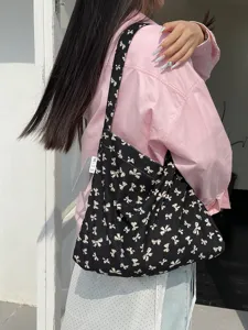 Detailed shot of a black canvas shoulder bag with cute white bow prints, soft fabric and sturdy strap.