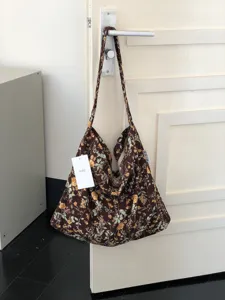 Detailansicht der vintage floralen Canvas-Schultertasche hängend an einer weißen Tür.
