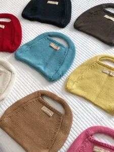 Detailansicht bunter Stricktaschen mit feiner Webtextur und eingenähtem Etikett.