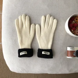 Detailaufnahme zweifarbiger Strickhandschuhe mit Plüschbündchen, weiche Textur und warmes Design.