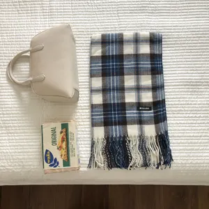 Gemütlicher blauer Karoschal mit Fransen im Detail flachgelegt für die Damen Wintermode
