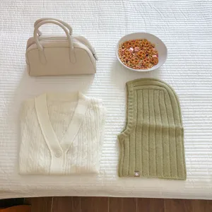 Winter knitwear detail view showing cozy cardigan, stylish balaclava hood and trendy bag.