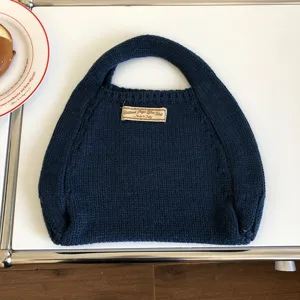 Klassisches Detail einer dunkelblauen Strickhandtasche mit weicher Textur für den Alltag.