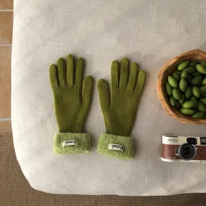 Nahaufnahme von herbstlichen grünen Strickhandschuhen mit kuscheligen Plüschbündchen Detail.