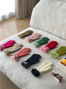 Nahaufnahme bunter Strickdamenhandschuhe mit Plüschbündchen, ordentlich auf Sofa arrangiert.