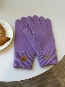 Detailed view of winter warm purple knit gloves with cute bear and letter embroidery.
