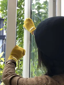 Vista detallada de mitones de punto amarillo con guantes de invierno cálidos junto a la ventana.
