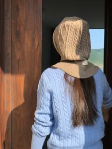 Detailed view of the cozy cable-knit hooded scarf in khaki, showing texture and lifestyle scene.