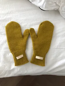 Manoplas de lana de punto para invierno en amarillo mostaza, vista detallada suave.