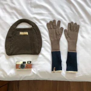 Detail view of knitted color-block long gloves and matching hobo handbag set for women.
