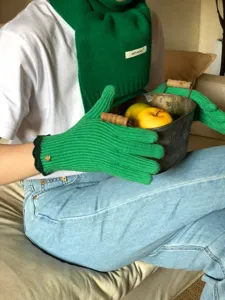 Nahaufnahme Detail des grünen Woll-Strickschals und Touchscreen-Handschuh-Sets Szenenansicht.