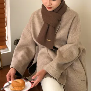 Brauner gerippter Strickschal im Detail, warmes Winteraccessoire mit Metalletikett.