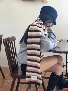 Dettaglio di sciarpa invernale a righe in mohair con morbida trama e etichetta.