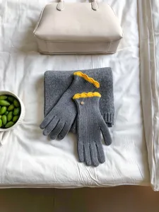 Detailansicht der grauen Winter-Strickhandschuhe mit gelben, wellenförmigen Bündchen.