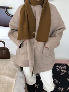 Gemütlicher Wollmantel und Strickschal Detail in warmen Brauntönen für kalte Tage.