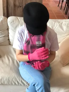 Detailansicht der warmen rosa Strickhandschuhe und des karierten Wollschals im Alltag.