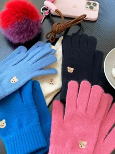 Dettaglio ravvicinato dei guanti touchscreen in maglia ricamati con orsetto per l'inverno.
