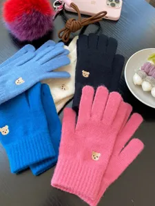 Primo piano di guanti lavorati a maglia con ricamo di orsetto e funzione touch screen.