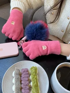 Primo piano dettagliato di guanti in maglia rosa con ricamo di orsetto per un accogliente stile invernale.