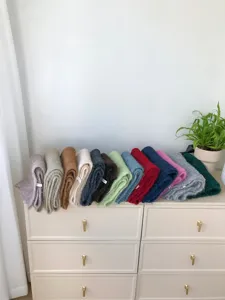 Detailansicht mehrerer gefalteter einfarbiger Mohair-Schals ordentlich auf einer modernen Kommode.