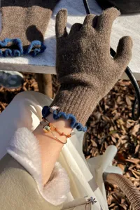 Detail view of winter touchscreen knitted gloves with blue ruffle cuffs and soft wool fabric.