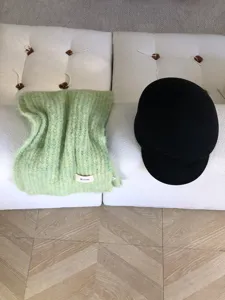 Detailaufnahme eines flauschigen grünen Mohair-Schals mit Etikett und schwarzer Mütze