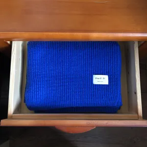 Blauer dicker Strickschal ordentlich in der Schublade gefaltet als warmes Winteraccessoire.