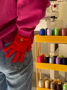 Dettaglio guanti in maglia rossa con grazioso patch di orsetto e sfondo da laboratorio.