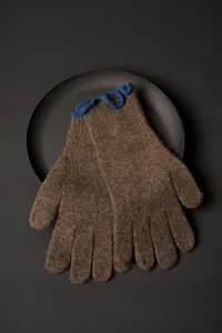 Close-up detail of brown wool knit gloves with blue ruffle cuffs, cozy winter handwear.