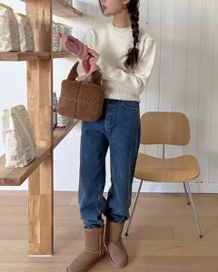 Detail view of stylish brown teddy fleece handbag in cozy lifestyle wooden room setting.