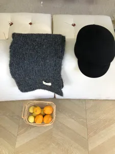 Gemütlicher dunkelgrauer Mohair Winterschal kombiniert mit schwarzem Hut im Detail.