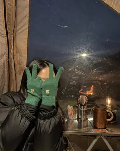 Primo piano di guanti invernali verdi in maglia con ricamo di orsetto grazioso e morbidi.